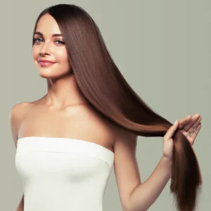 A woman in a white strapless top holding a section of her long, straight brown hair.
